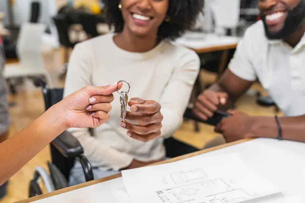 Remise des clés à un couple d'acquéreurs, plan d'appartement sur la table